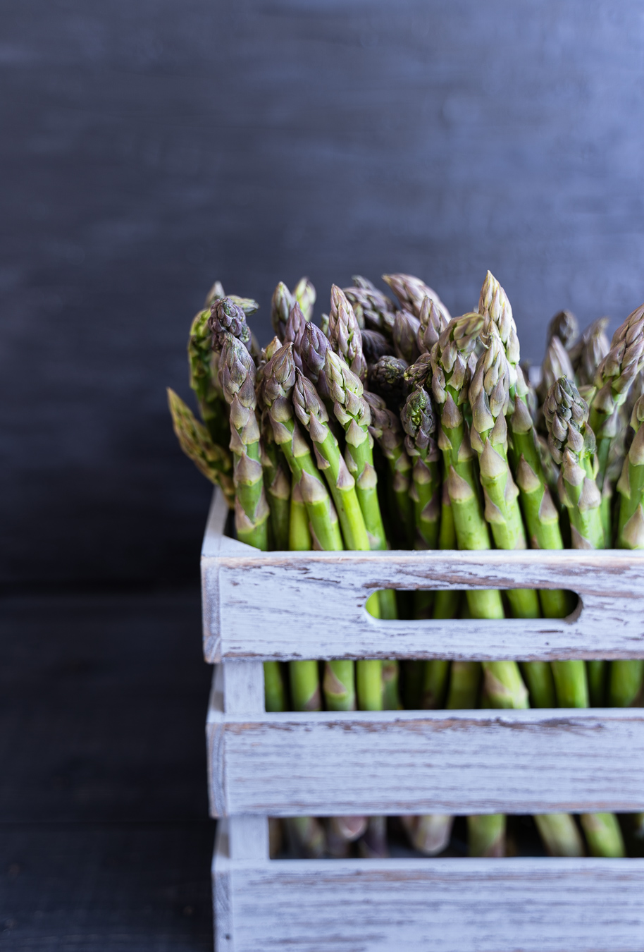 Raw asparagus tips in wooden crate — Greens & Salads