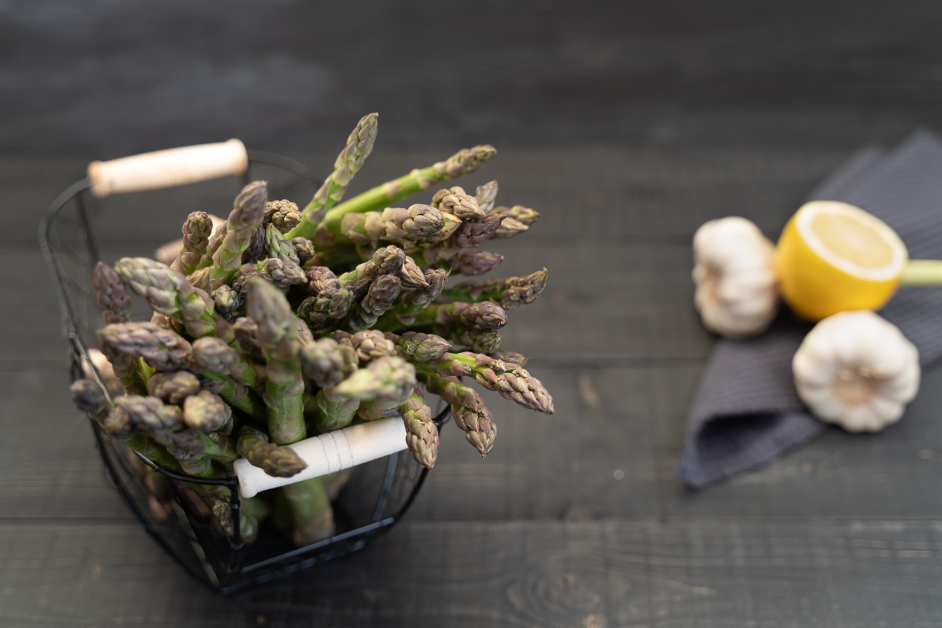 Raw asparagus tips in wire basket with lemon and garlic — Greens & Salads