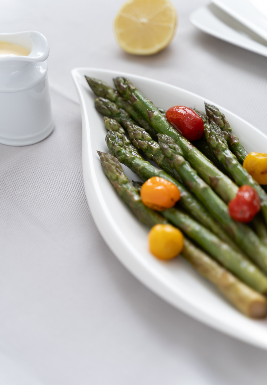 Green asparagus with cherry tomatoes on leaf plate — Green Kitchen