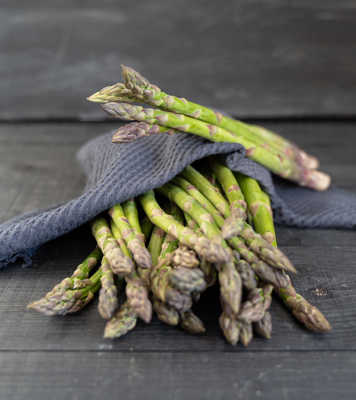 Raw asparagus wrapped in grey cloth — Greens & Salads