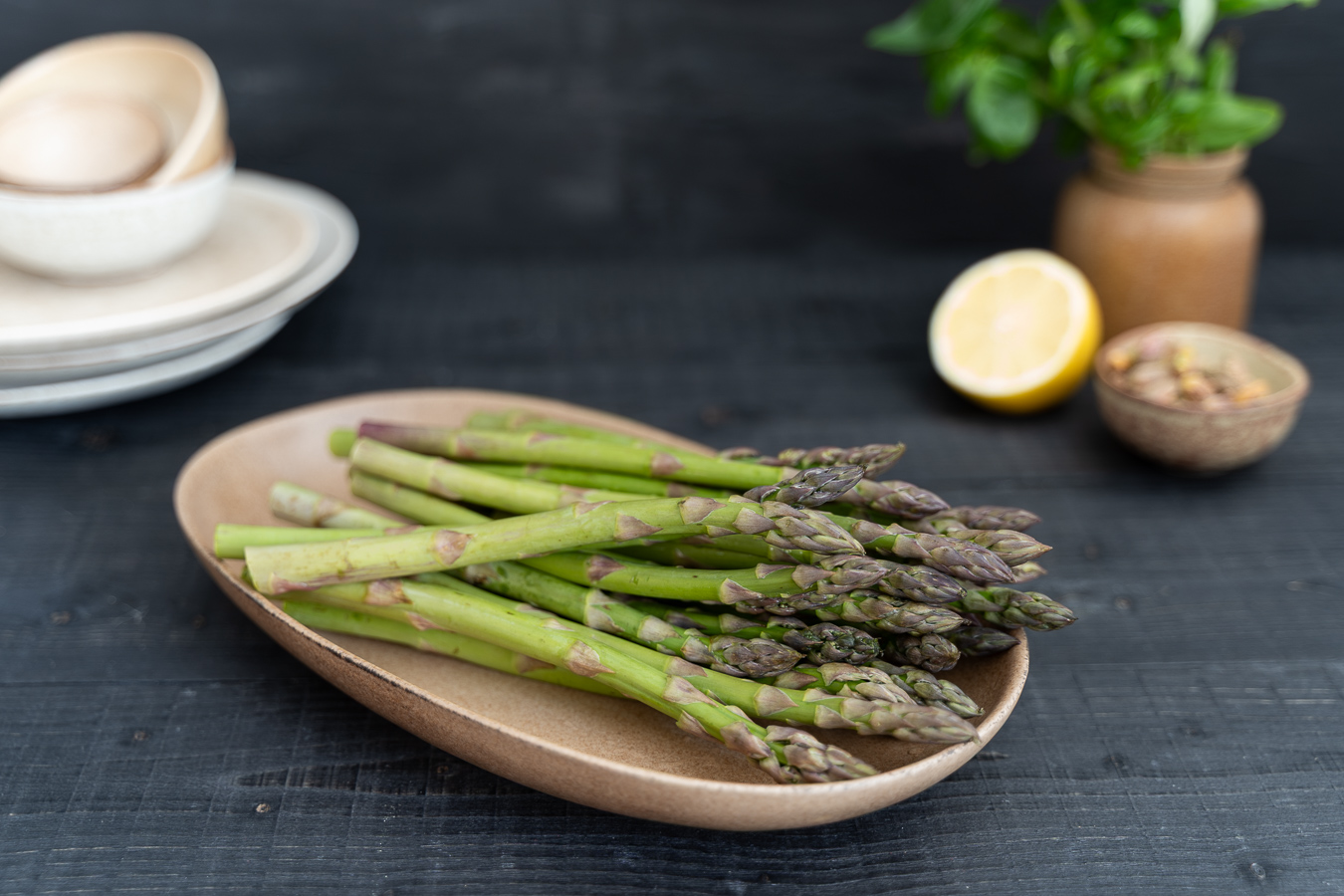 Raw asparagus stalks on tan ceramic — Greens & Salads